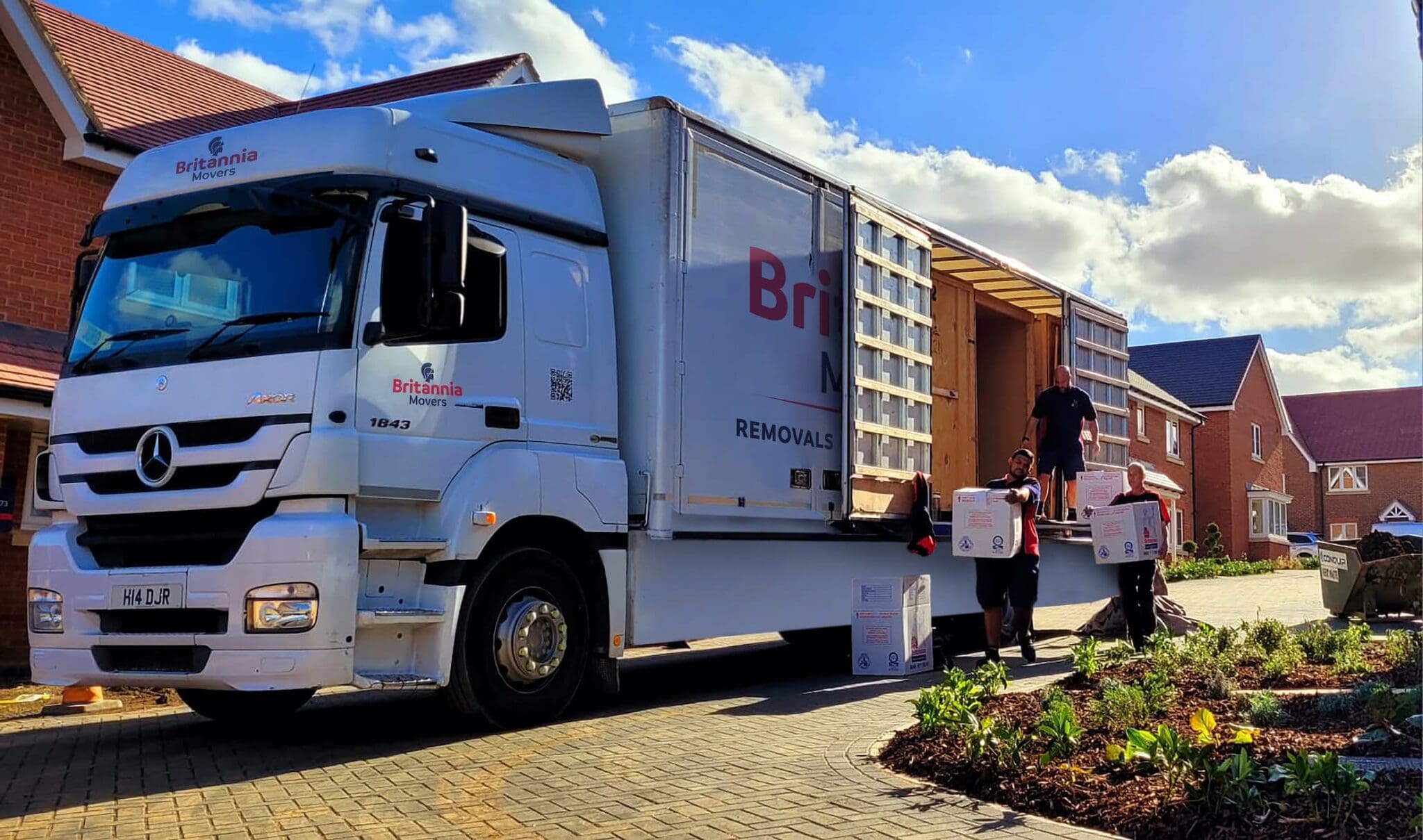 A white removal van parked outside a house being unloaded